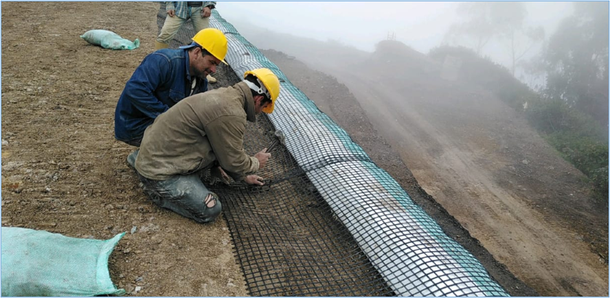 Instalación y anclaje de geomalla durante la construcción de un muro en suelo reforzado.