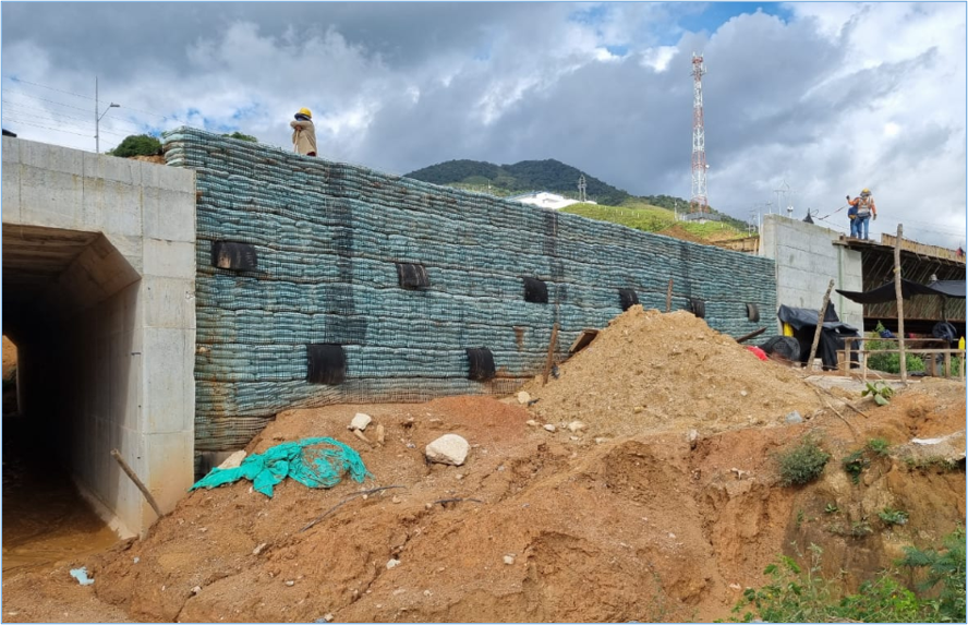 Muro en suelo reforzado construido entre estructuras rígidas en proyecto de infraestructura.